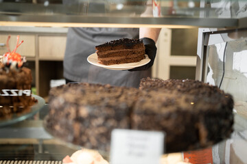 shop with sweets chocolate cake and a piece. Showcase of cake, beautiful glass display, various dessert at bakery shop in department store, popular food business in the city