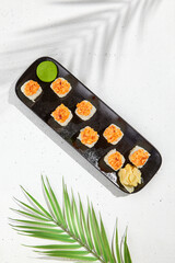 Maki sushi with salmon top on black plate. Sushi roll with philadelphia cheese inside and salmon tartare outside. Maki roll in minimal concept. Summer menu for japanese restaurant.