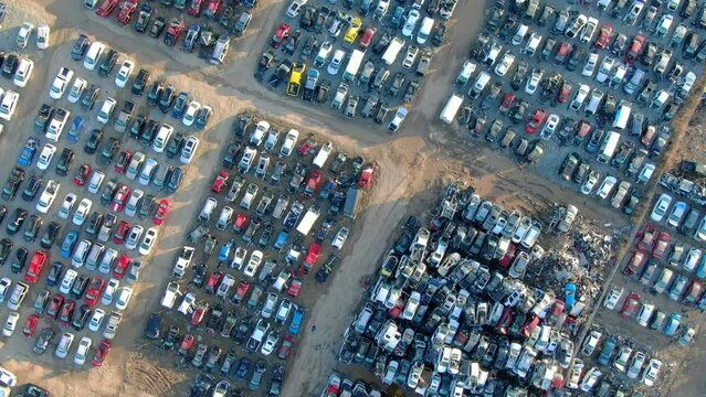 Looking straight down on thousands of smashed cars, trucks, SUVs reduced to scrap metal, spare parts, in junkyard, aerial view.