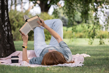 girl reading a book on the lawn - 502777091