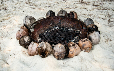 Charcoal grill for BBQ on the beach decorated with mature coconut.