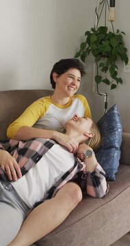 Vertical video of happy caucasian lesbian couple embracing at home