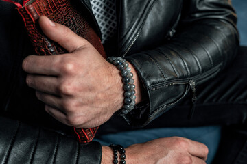 Men's bracelets made of natural stones and minerals, close-up, on the hand. - obrazy, fototapety, plakaty
