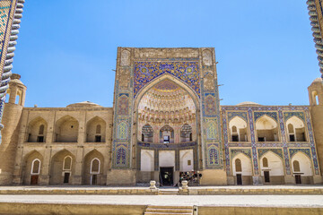 Fototapeta na wymiar Facade of Abdulaziz Khan Madrasah in Bukhara, Uzbekistan. Built in 17th century. Together with Ulugh Beg madrasah (part of portal is visible on sides of photo) they make up the Kosh-madrasah complex