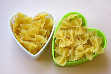 Butterfly shaped pasta stacked in a heart shape on the table.