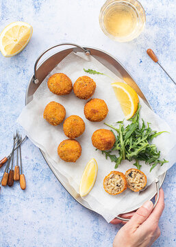 Anonymous person with arancini rice balls placed on metal tray on table