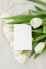 Obraz na płótnie Canvas Bouquet of white tulips with card. Vertical menu card mock up, name card, place card, wedding invitation mock up