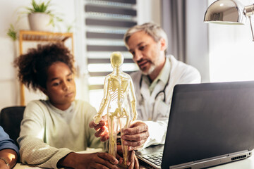 Mother And Daughter Having Consultation With Male Pediatrician In Hospital Office