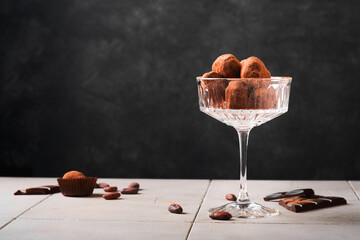 Chocolate truffles. Homemade chocolate truffles with cocoa powder on glass on old cracked tile table background. Tasty sweet chocolate truffles candies. Valentine's Day and Mother's Day concept.