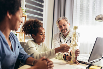 Mother And Daughter Having Consultation With Male Pediatrician In Hospital Office