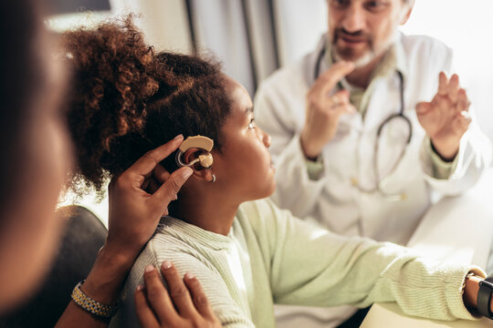 Smiling Deaf African American Girl With Ear Implant At Doctor's Office.