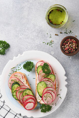 Toast with cheese and radish. Sandwiches with cottage cheese, radish, cucumber and green onions on gray concrete background. Healthy spring sandwiches. Traditional Scandinavian toast. Top view.