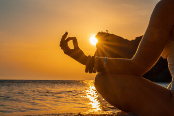 Woman tourist enjoying the sunset over the sea mountain landscape. Sits outdoors on a rock above...