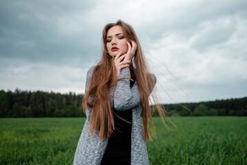 Girl with long hair stands in field in the wind. The concept of freedom and passion.