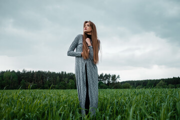 Girl with long hair standing in field in the wind.