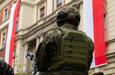 Polish army soldier during 3 May Constitution Day ceremonial patriotic parade. Military troops at celebration of the 3rd May National Holiday, with flags of Poland in background.