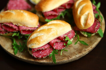 Selective focus. Macro. Salami sandwiches with arugula and mustard on a wooden board.