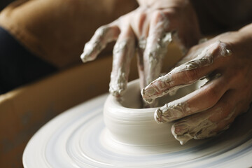 Close up potter's hands making clay vase on pottery wheel, ceramic studio