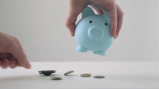 Hands shaking coins out of piggy bank. Use last savings, unemployment and bankruptcy concept. Crisis and dismissal. Checking piggy box content on a desk 