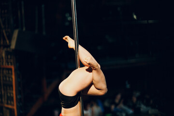 Woman striptease dancer dancing pole dance on scene.