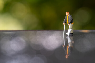 Miniature people man with broken leg is using crutch For Walking