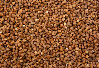 Макро фотография коричневой не приготовленной гречневой крупы  Фон с текстурой мелкой гречневой крупы 