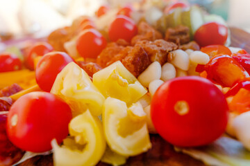 cherry tomatoes, sweet peppers,  pickled cucumbers, pickled garlic, olives,  sausage, different cheese, bacon on wooden plate. Snack food