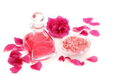 Obraz na płótnie Canvas Rosewater in art deco glass bottle with flower, petals and Himalayan salt for exfoliation beauty treatment. Natural skincare concept to restore skin ph balance. On white background. Rosa rugosa. 
