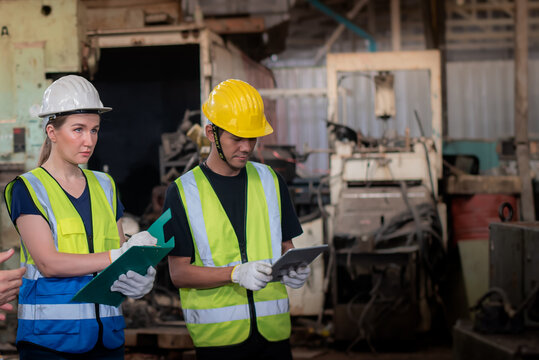 Inspector Engineer Woman and technician in safety uniform holding checklist and digital tablet working in heavy industrial manufacture factory.
