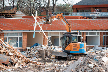 Demolition of an old building with an excavator to give way for a new housing site and piles of...