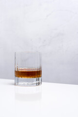 Un vaso de whisky sobre una mesa blanca y fondo claro	