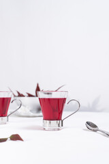 Dos tazas transparente de té de bayas sobre una mesa blanca y un fondo gris claro	