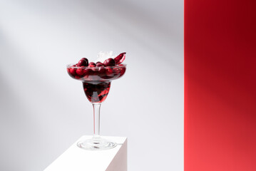 Cóctel Margarita de arándanos rojos sobre un soporte blanco y fondo gris	