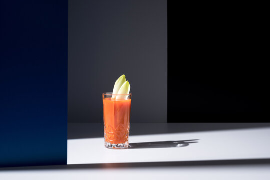 Vaso de jugo de zanahoria con hojas de endibia sobre fondo oscuro	