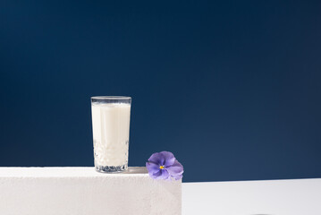 Un vaso de leche fresca de vaca sobre piedra de hormigón blanco y fondo azul	