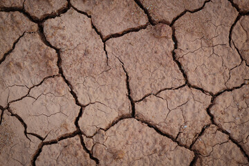 Top view cracked red soil. Picture of natural disaster. Drought land, global warming and deforestation. Image of brown soil texture, close up.