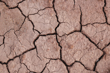 Top view cracked red soil. Picture of natural disaster. Drought land, global warming and deforestation. Image of brown soil texture, close up.