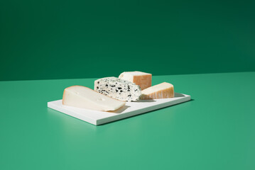 Surtido de quesos franceses. Queso de leche de cabra, vaca y oveja sobre un fondo verde - obrazy, fototapety, plakaty