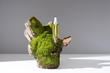 Botella de aceite esencial con cuentagotas sobre un tronco de árbol con musgo. Producto cosmético...