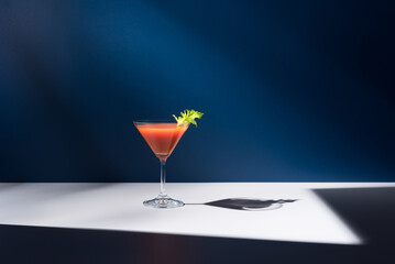 Coctel Bloody Mary decorado con hoja de apio sobre fondo azul	