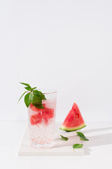 Un vaso de zumo de sandía con trozos de sandia y hielo sobre fondo claro	