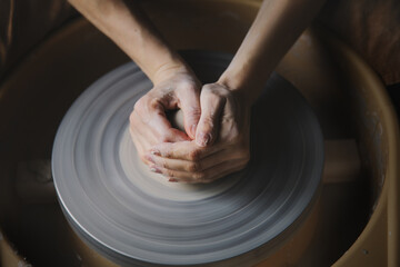 Female hands making futture vase or bowl on pottery wheel, ceramic studio workshop, working with clay on potter's wheel