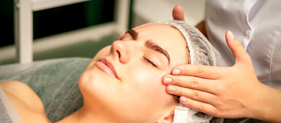 Head massage. Beautiful caucasian young white woman receiving a head and forehead massage with...