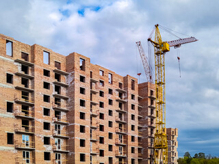 Fototapeta na wymiar Residential brick house under construction. Unfinished house and tower crane. New multi-storey building