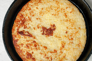 Swiss traditional dish - potato pancakes fried in a frying pan, close-up, top view.