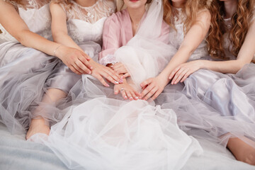 elegant bride with bridesmaids in the wedding morning preparation. Beautiful bride is dressed up an...