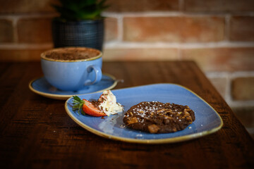 Overhead view of a chocolate and nut cookie with a hot chocolate on a table
