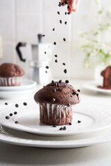 unrecognizable woman's hand throwing chocolate chips on a homemade cupcake