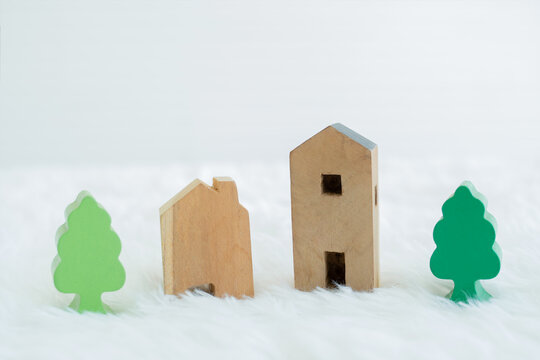 Small wooden model house and building with green trees in residential areas. Coexistence with nature concept. White background