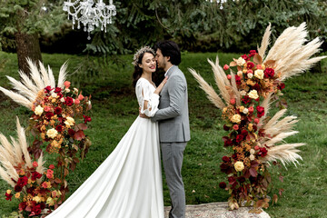 Beautiful wedding couple hugging and kissing at the wedding ceremony on the background of the forest
